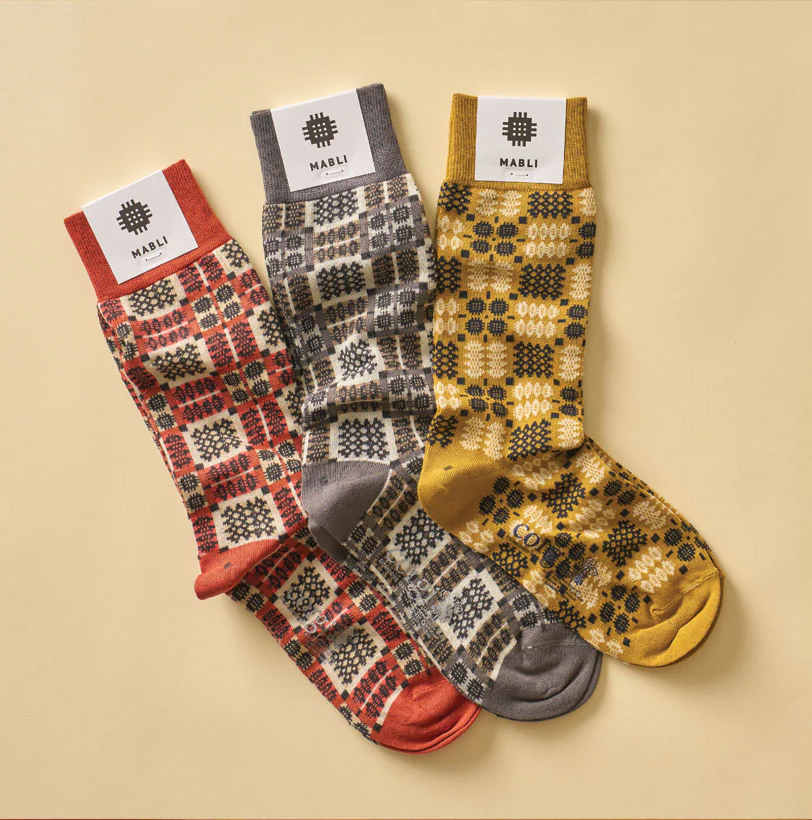 Photograph of three pairs of patterned socks in red grey and yellow